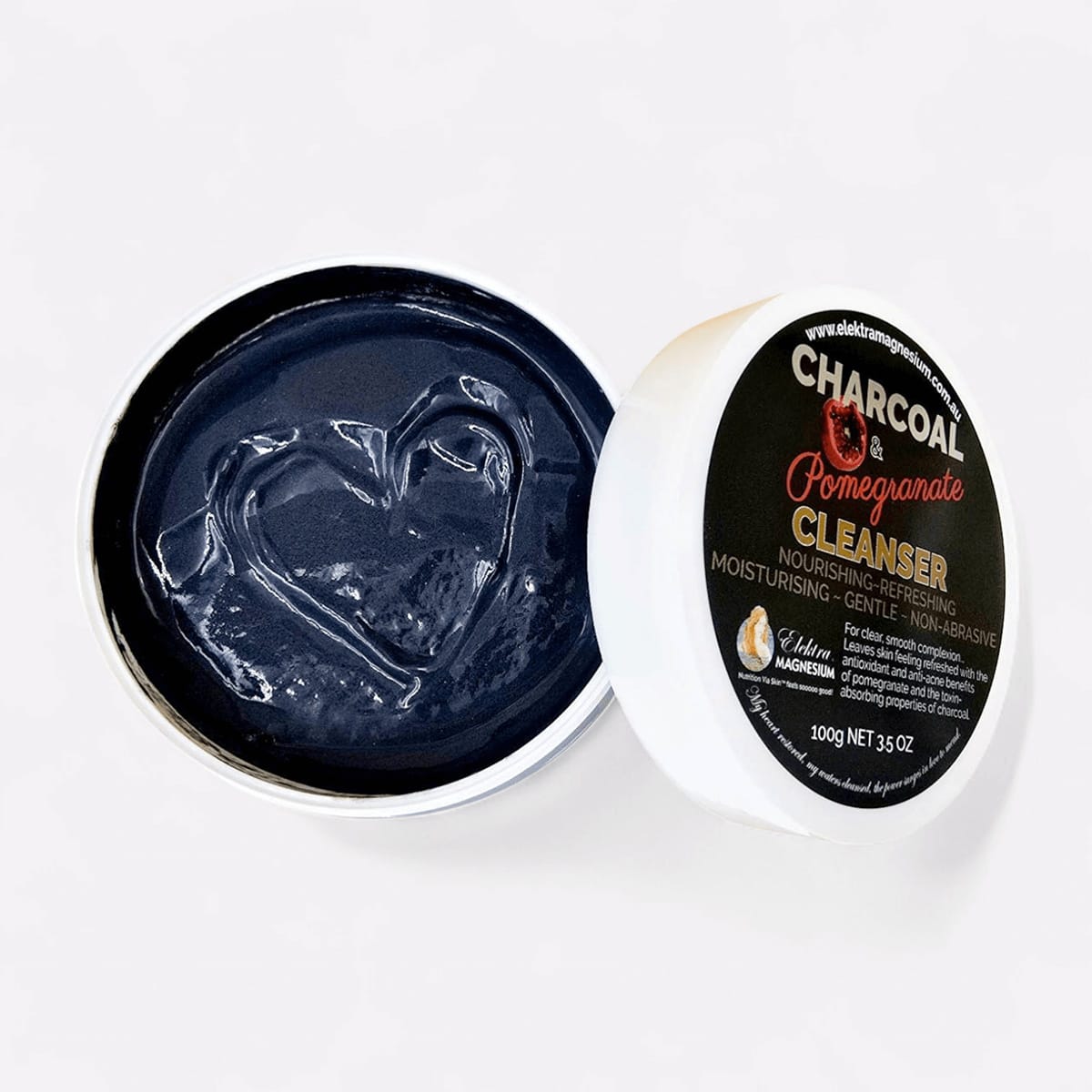 An open jar of Elektra Magnesium Charcoal-Pomegranate Cleanser, a natural facial cleanser for detoxifying and exfoliating